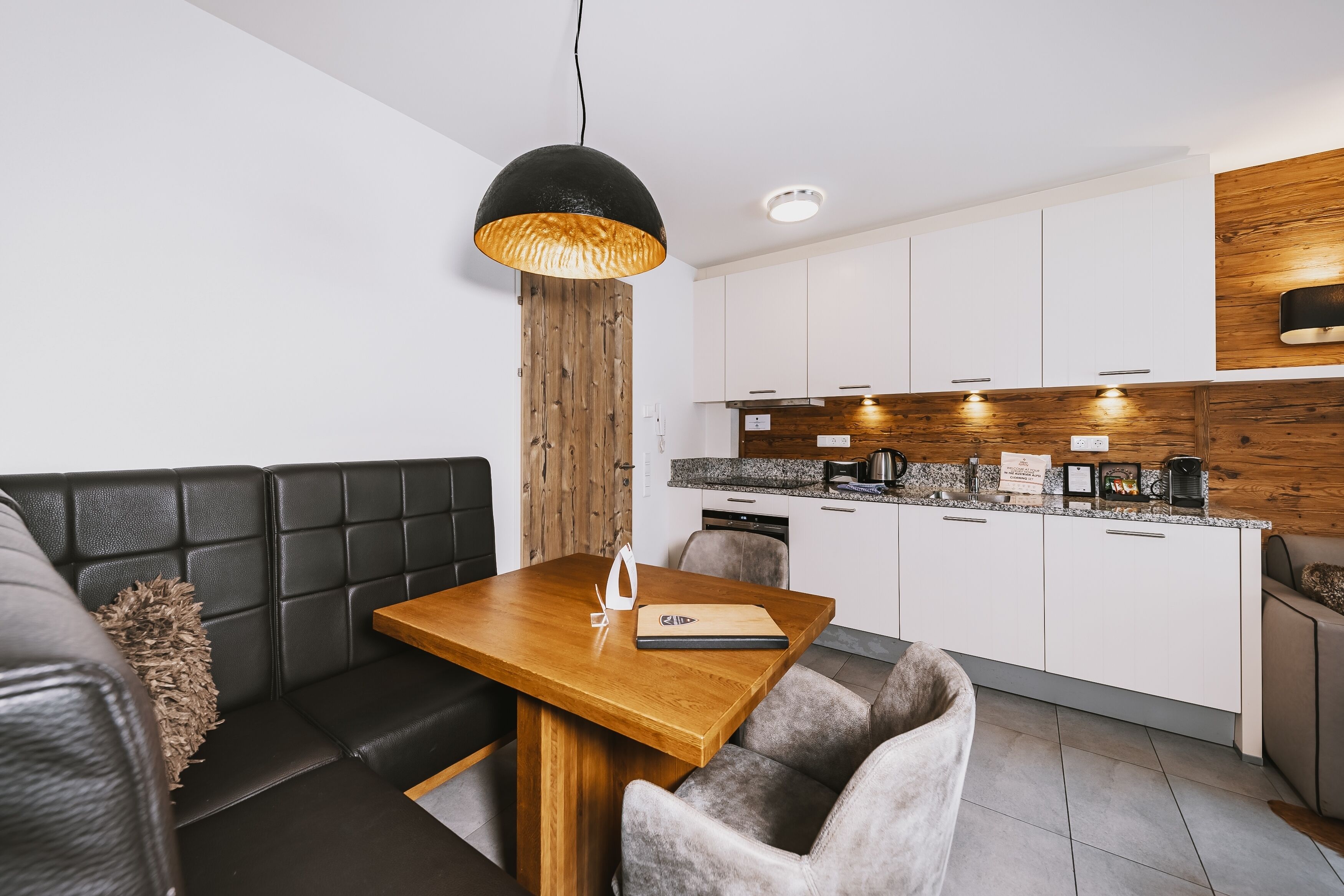 A modern kitchen with white cabinets, a wooden accent wall, and a built-in oven.