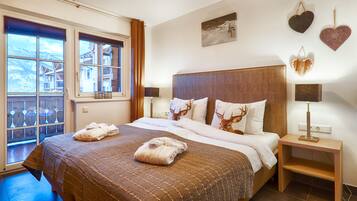 A hotel room with a large bed, two pillows with deer prints, a bedside table with a lamp, and a window with a view of a building.