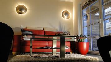 A modern living room with a red sofa, a glass coffee table, and two wall-mounted lights.