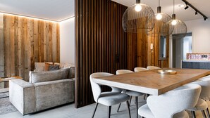 A modern dining area with a wooden table and chairs, a sofa, and pendant lighting. - AvenidA Mountain Resort by Alpin Rentals - incl Summercard (Kaprun)