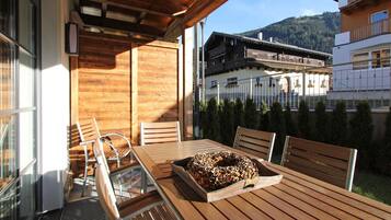 A wooden table with a tray of food, chairs, and a view of a mountain and buildings.