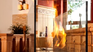 Un interior moderno con un separador de vidrio, una chimenea y una pared de piedra.