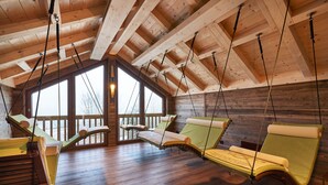Una habitación con vigas de madera, ventanas amplias y cuatro camas colgantes.