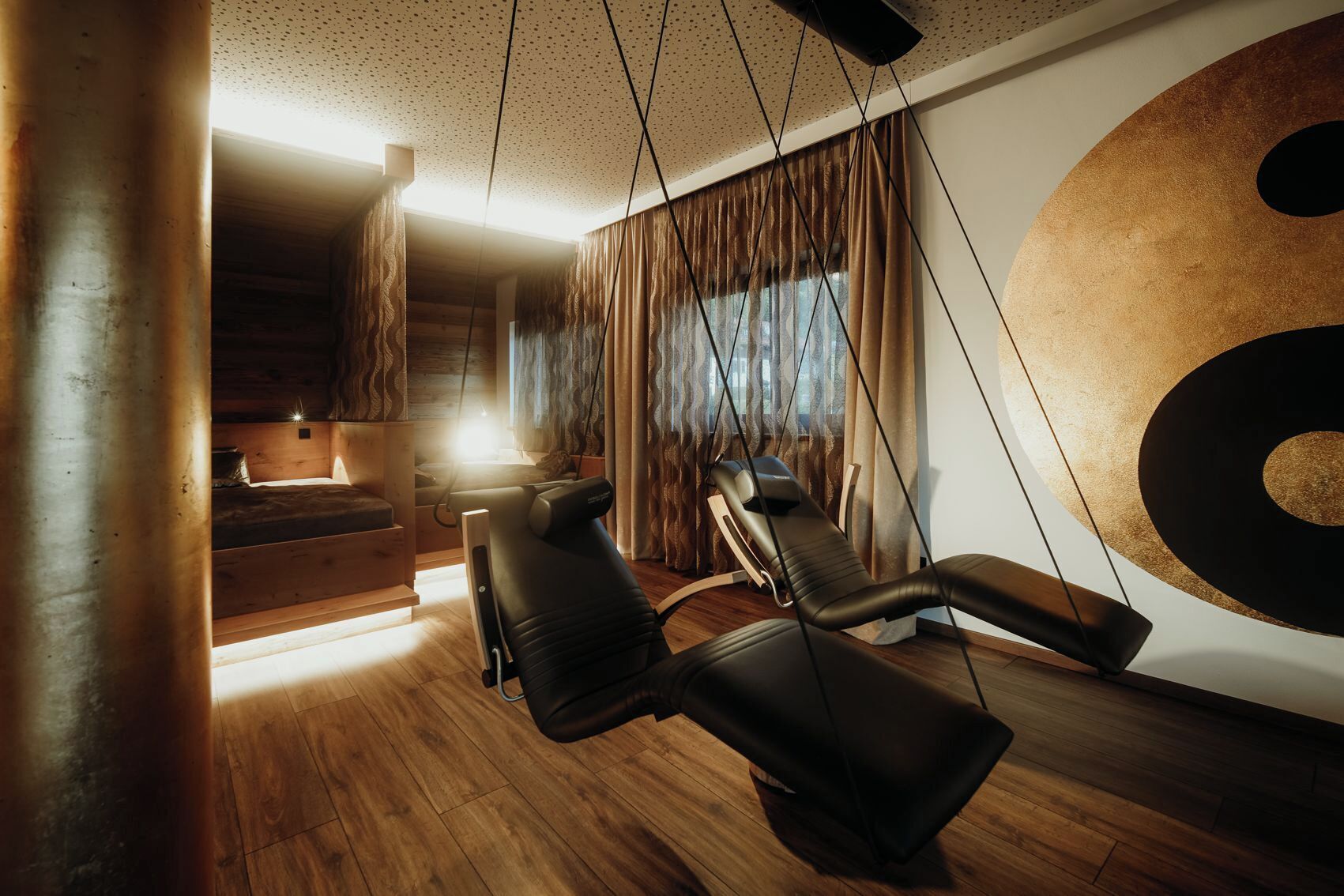 Un moderno spa con suelo de madera, una amplia sillón de masaje instalado en la pared y una ventana con cortinas.