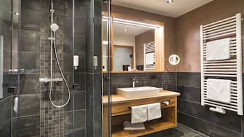 Un bagno moderno con doccia vetro, mobile bagno in legno, uno specchio grande e un portasciugamani.