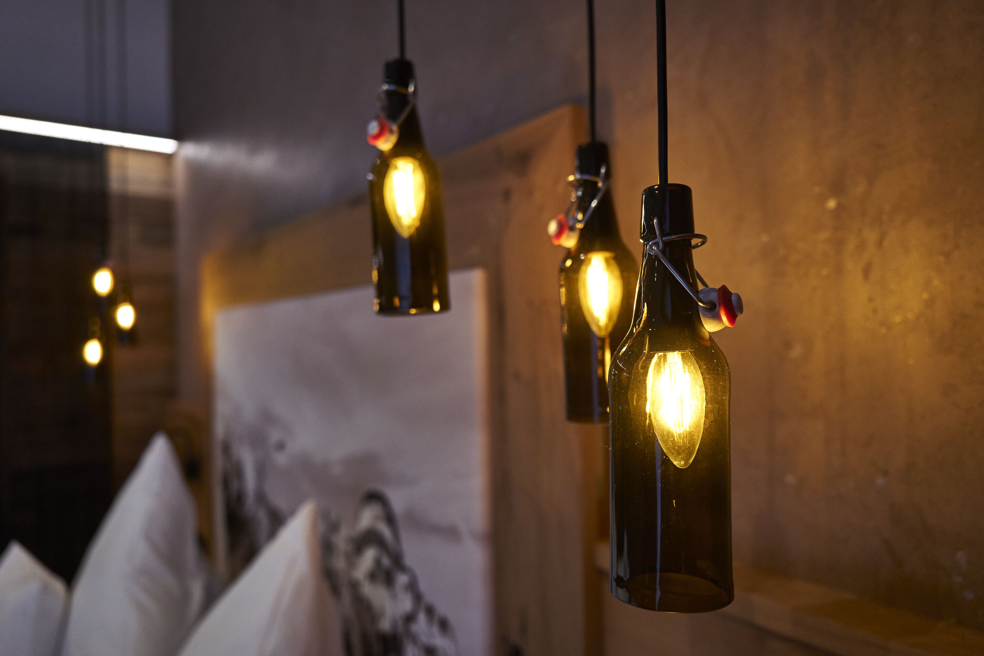 Pendant lights with exposed bulbs in a room with a wooden wall and a large framed picture.