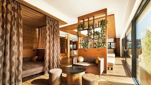 Een moderne woonkamer met houten vloeren, een bank, poefjes en een salontafel.