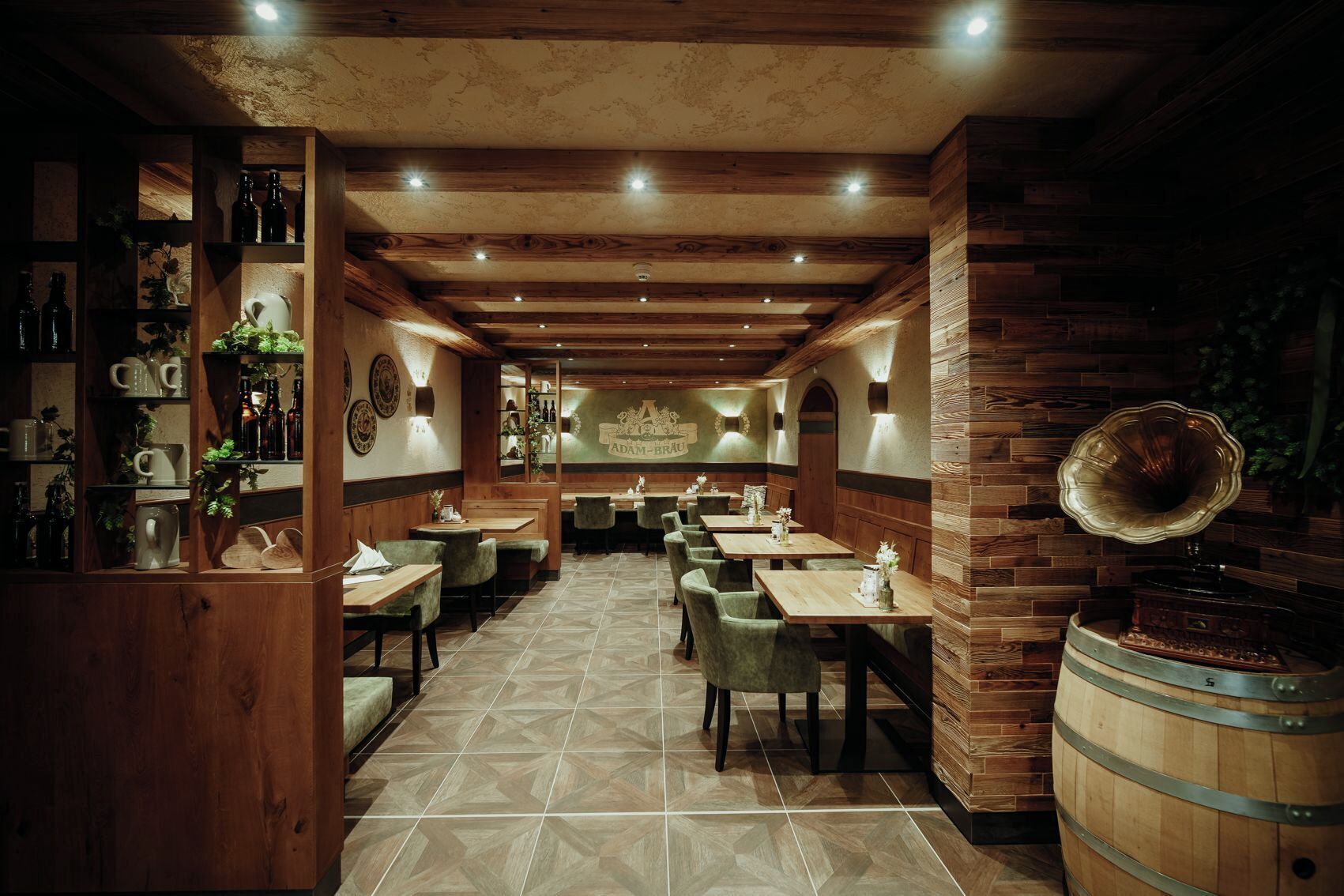 A restaurant with wooden walls and ceiling, multiple tables and chairs, and a bar area with bottles and glasses.