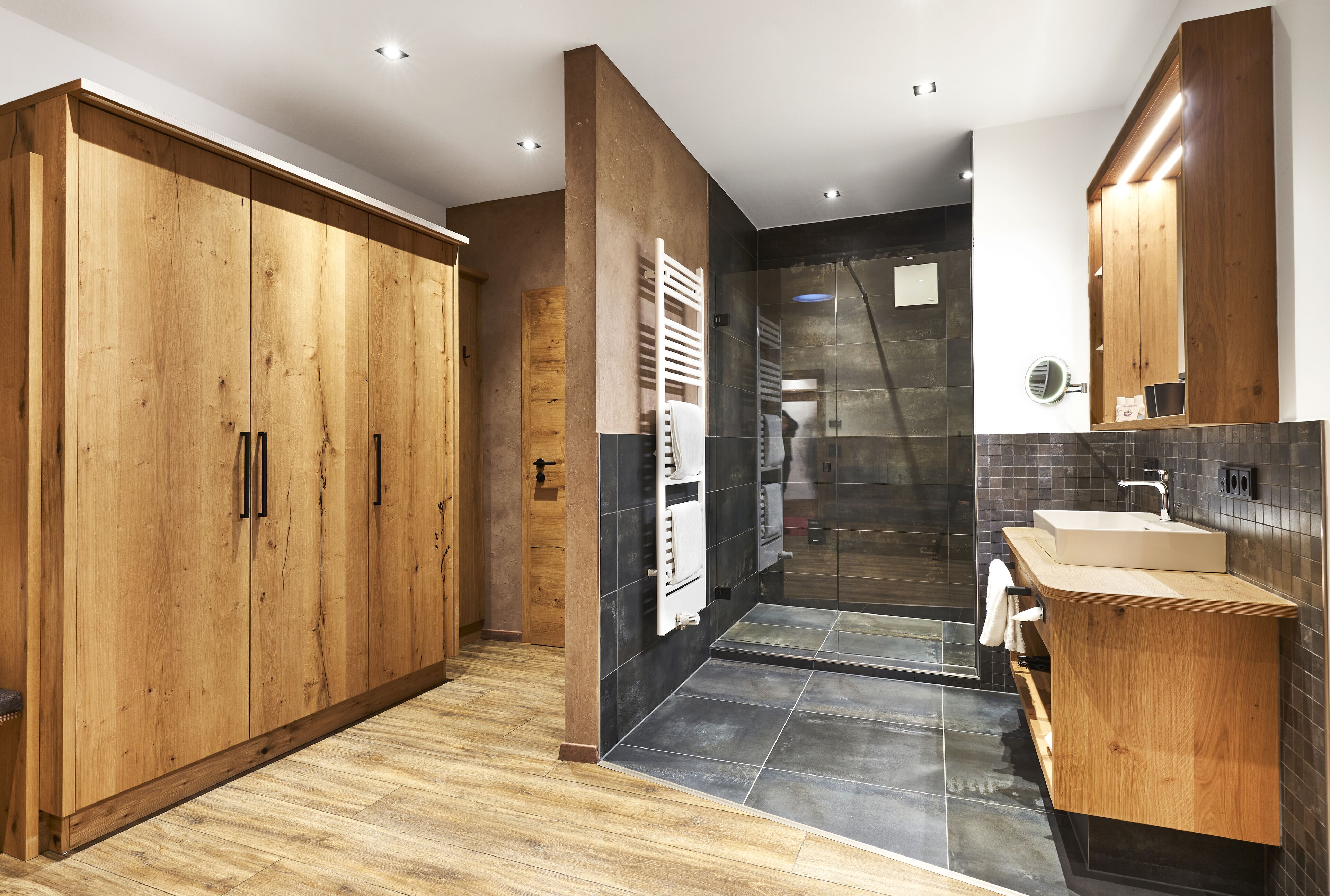 A modern bathroom with wooden cabinets, a glass shower, and a built-in sink.