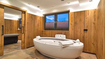 A modern bathroom with a freestanding bathtub, wooden paneling, and a window with a view.