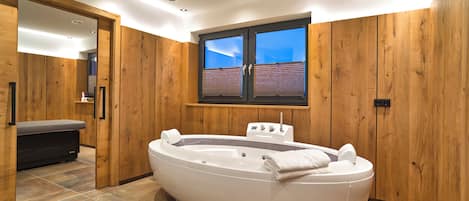 Un baño moderno con una bañera independiente, paneles de madera y un ventanal con vistas.
