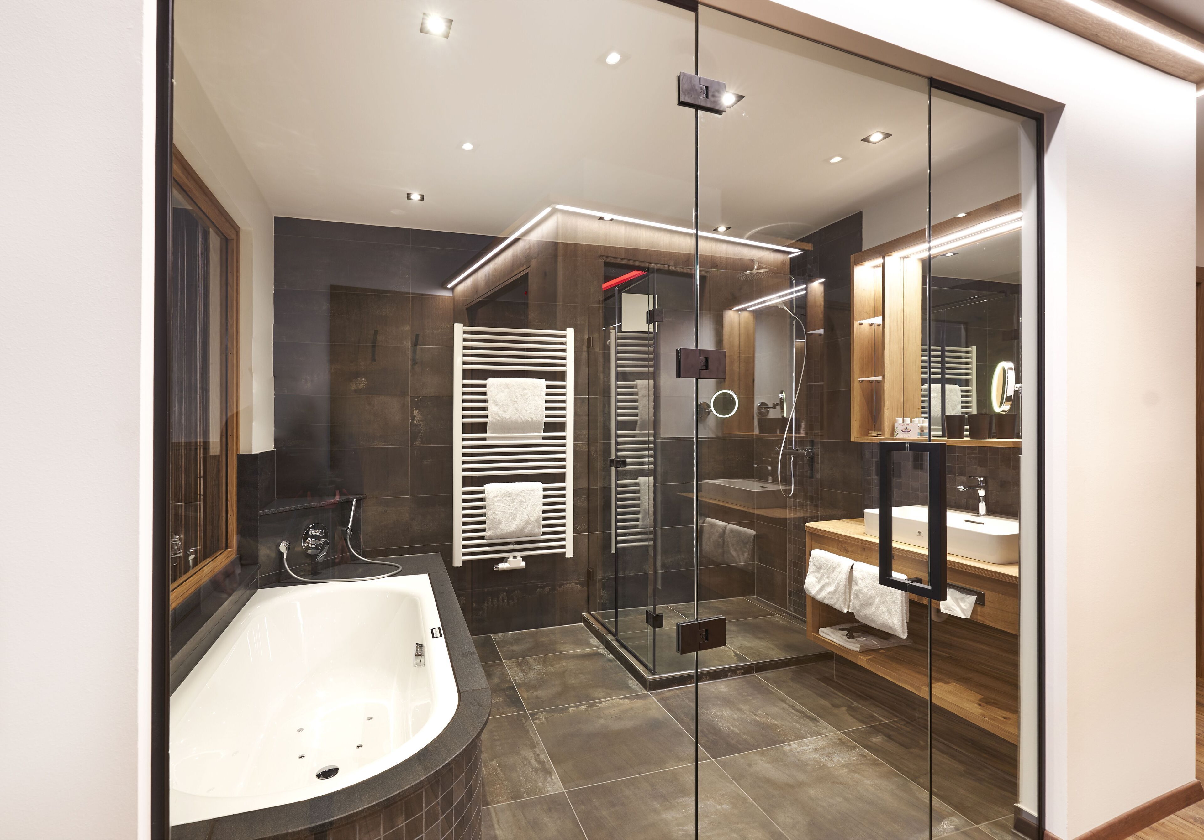 A modern bathroom with a glass-enclosed shower, a freestanding bathtub, and a vanity with a mirror.