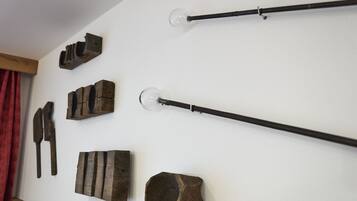 A wall with various wooden objects, including a long black rod with a glass bulb at the end, a wooden block with a handle, and several other wooden items.