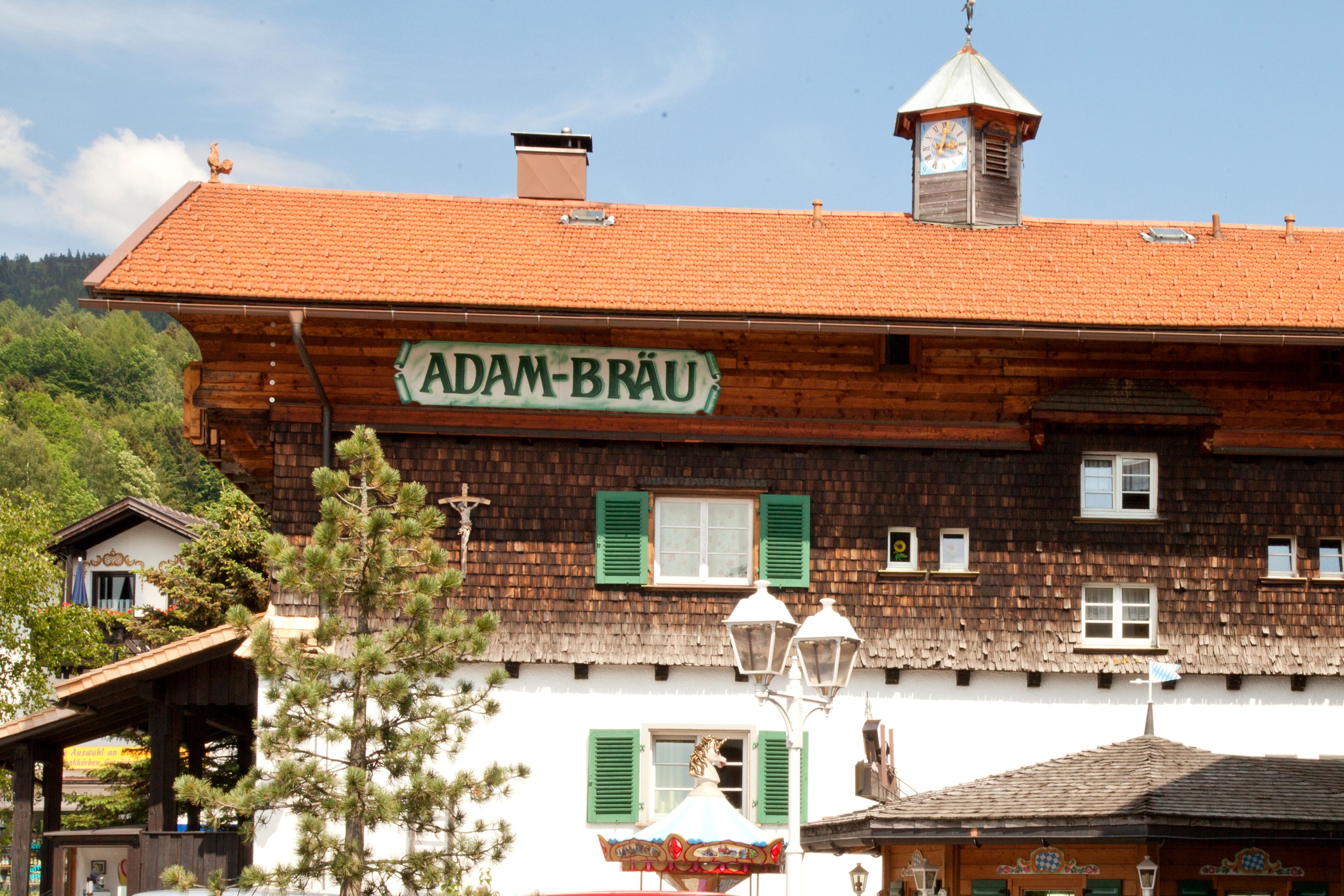 A traditional wooden building with a sign reading "ADAM-BRÄU".