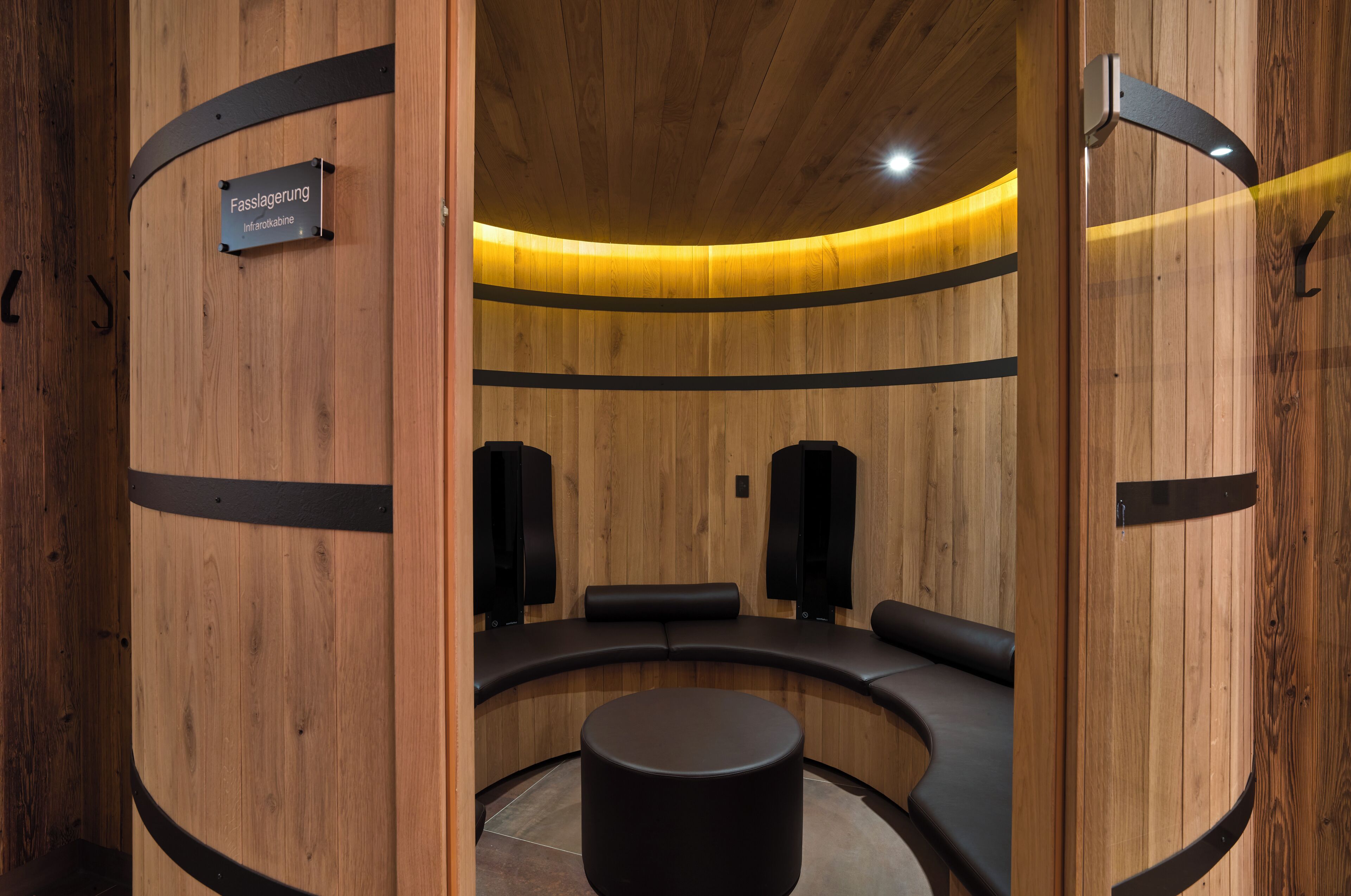 Un intérieur en bois avec un espace salon aux lignes courbes, une petite table et deux haut-parleurs.