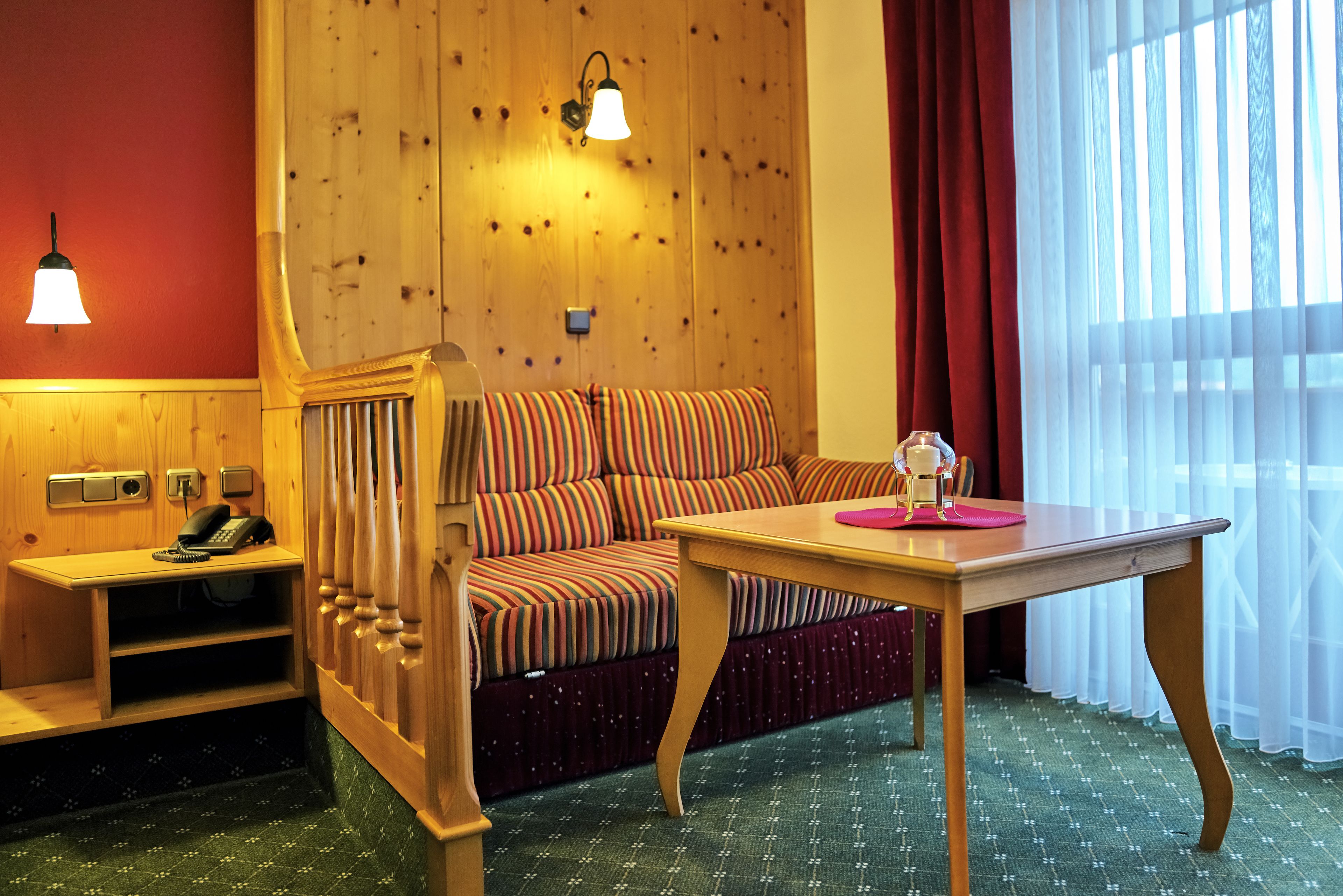 Une pièce comprenant un banc en bois, un canapé à rayures, une table et un téléphone.