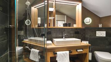 Une salle de bain moderne avec une douche à parois de verre, un meuble-lavabo en bois doté d’un grand miroir et des toilettes blanches.