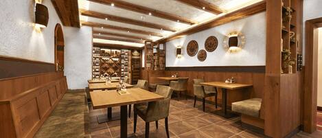 Um restaurante com cabines de madeira, mesas e uma parede com pratos decorativos.