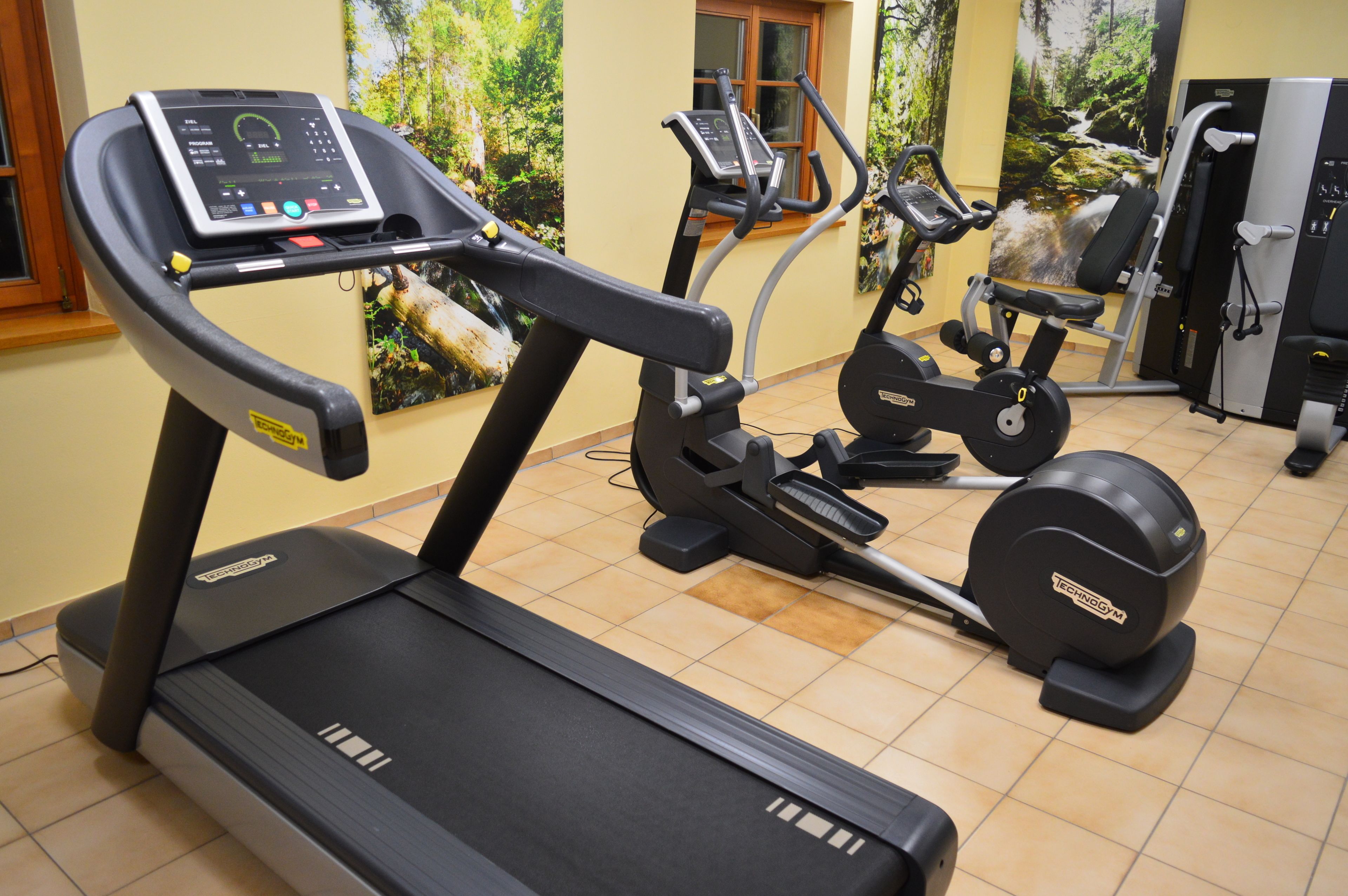 Gimnasio con cinta de correr, elíptica y máquinas de pesas.