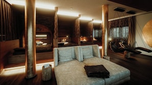 Een ruime kamer met een groot bed, meerdere zithoeken en een knus haardvuur.