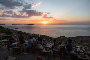 A sunset view from a deck with tables and chairs, overlooking the sea. - Hostal La Torre (Sant Antoni de Portmany)