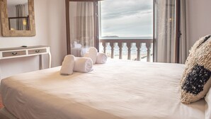 Una habitación de hotel con cama, escritorio, espejo y vista al mar.