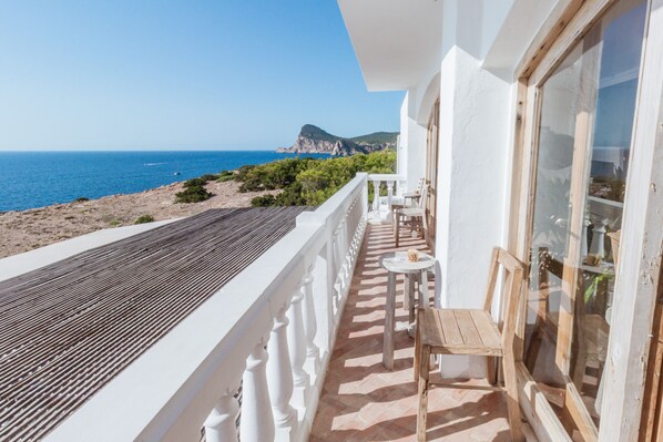 A balcony with a view of the sea and a mountain, furnished with a table and chairs. - Hostal La Torre (Sant Antoni de Portmany)