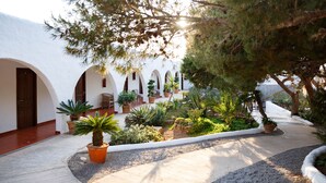 Un patio con plantas en macetas, un sendero y arcos blancos.