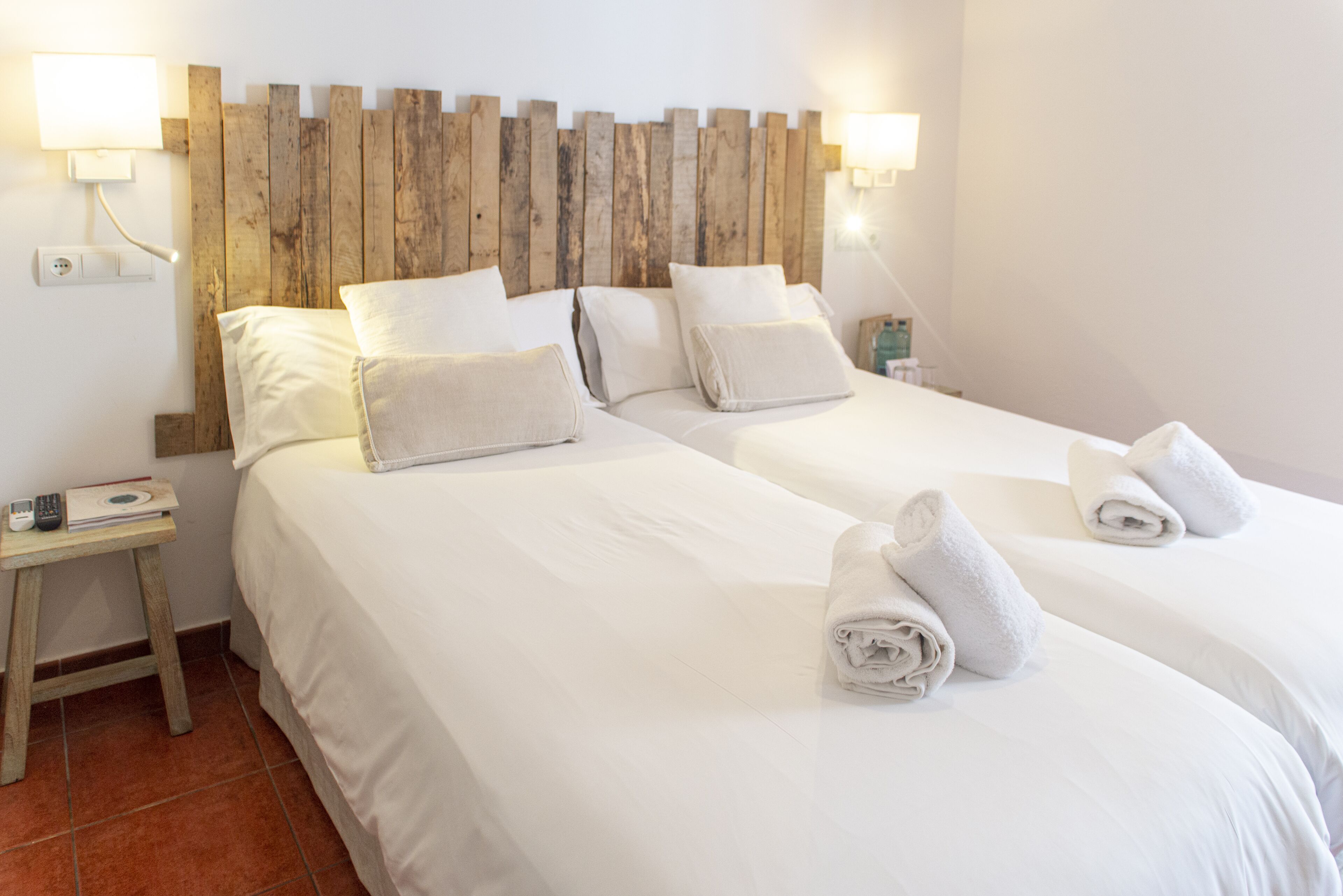 A hotel room with two beds, wooden headboard, white linens, and bedside lamps.