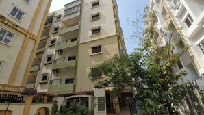 A multi-story residential building with balconies, a gated entrance, and a signboard.
