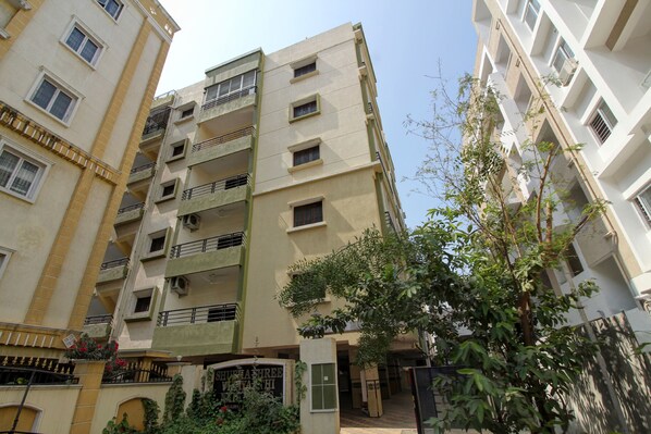 A multi-story residential building with balconies, a gated entrance, and a signboard.