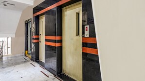 An elevator with a digital display, black and orange stripes, and a beige door.