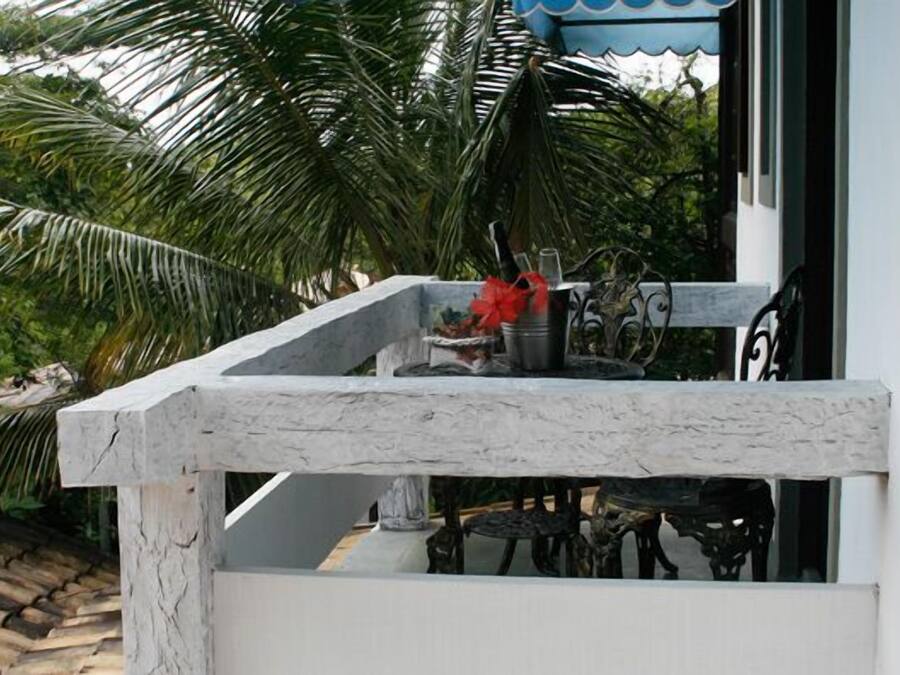 Een balkon met een stenen rand, een kleine tafel met decoratie, en uitzicht op palmbomen.