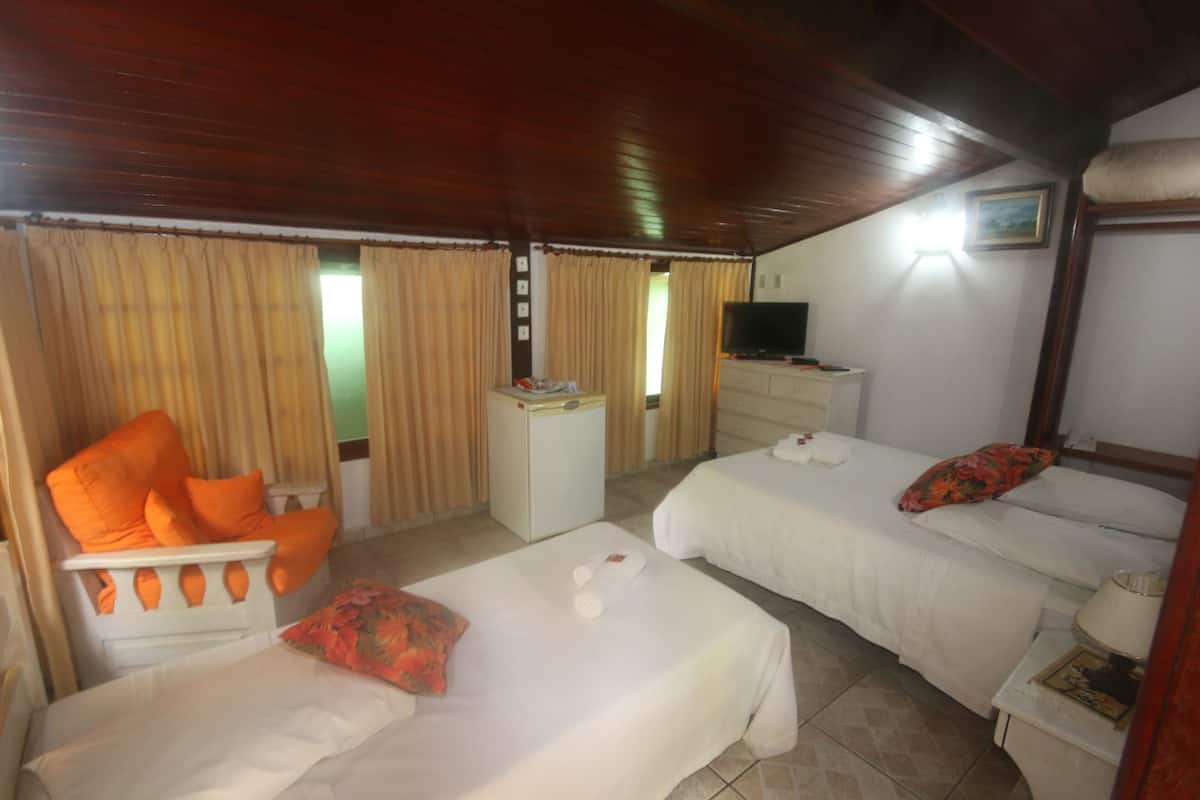Habitación de hotel con dos camas, un escritorio pequeño, televisor y ventana con cortinas.