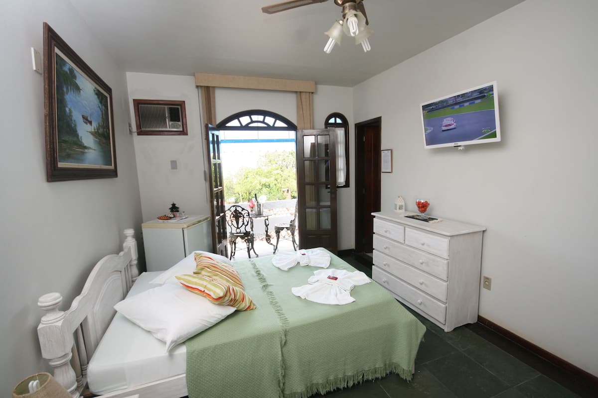 Un dormitorio con cama, cómoda, televisor y un cuadro en la pared.