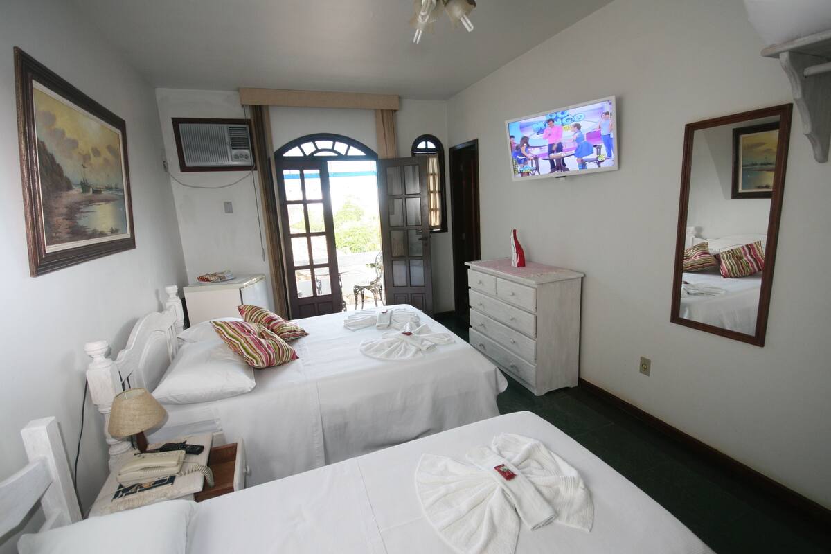 Habitación de hotel con dos camas, televisión, cómoda y un cuadro en la pared.