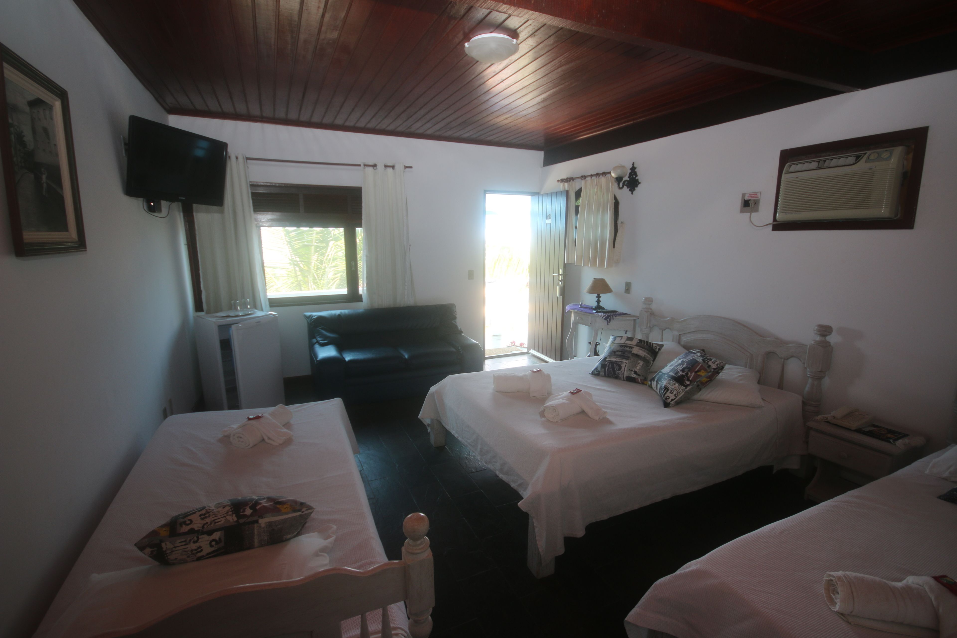 A hotel room with two beds, a television, a window with curtains, a desk, and a nightstand.