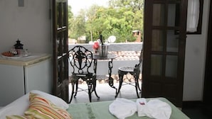 Ein Zimmer mit einem Bett, einem kleinen Tisch mit Stühlen und Blick ins Freie.