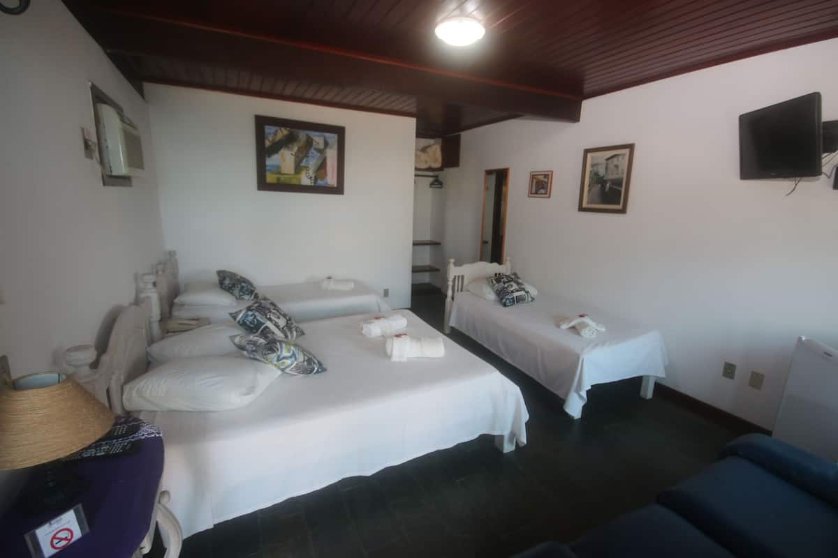 Habitación de hotel con dos camas, un televisor y un ventilador de techo.