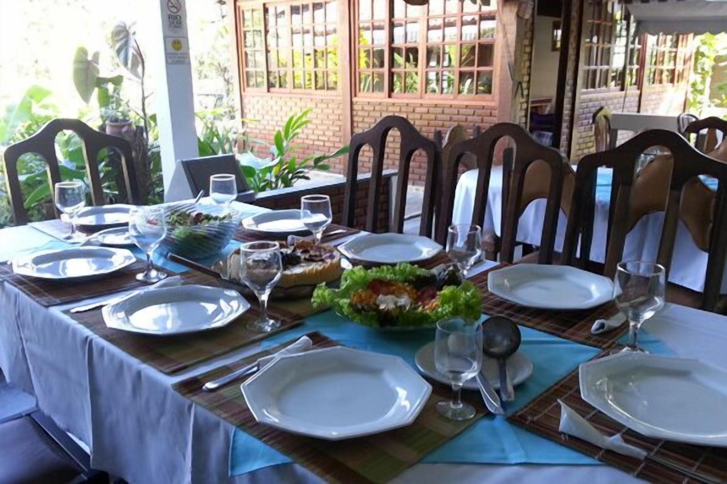 Une table mise pour le repas, avec des assiettes, des verres et une salade.