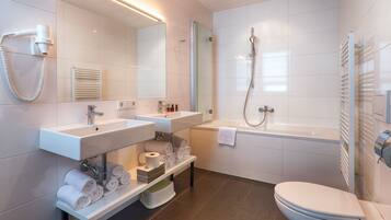 Un baño moderno con lavamanos, espejo, toallero, inodoro y ducha.