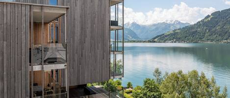 Ein modernes, mehrstöckiges Gebäude mit Balkonen mit Blick auf einen See und Berge.