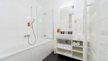 A modern bathroom with a bathtub, a glass-enclosed shower, and a vanity with towels and toiletries.