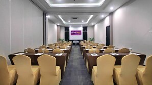 A conference room with multiple tables and chairs, a podium, and a banner reading "Quest Hotel."
