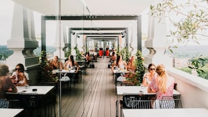 A rooftop dining area with tables and chairs, surrounded by greenery and overlooking a cityscape. - Dear Hotel Madrid (Madrid)