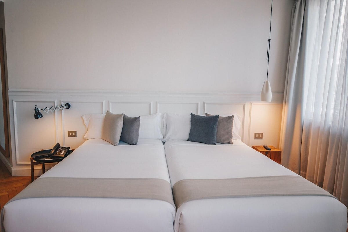 A double bed with white bedding, a bedside table with a lamp, and a phone.