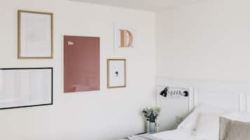 Un dormitorio con una cama, una mesita de noche con lámpara, y decoración en la pared que incluye letras y un cuadro enmarcados.