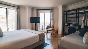 Habitación de hotel con dos camas, un televisor, una mesita con una silla y una estantería.