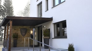 Een modern gebouw met een bordje met daarop 'Ski & Golf Suites' en een stenen inkom.