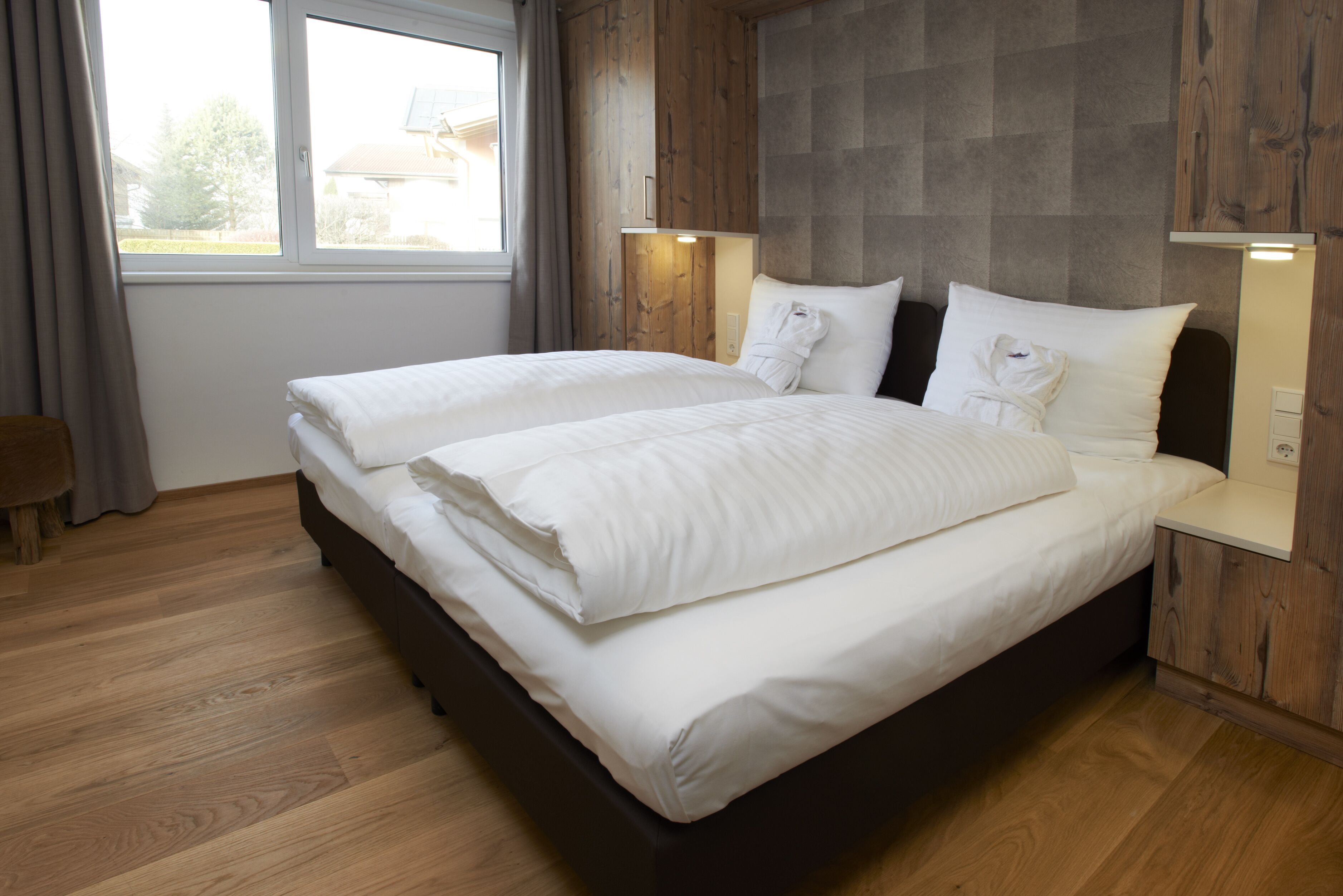 Una cama doble con ropa blanca, un cabecero de madera y lámparas de noche.